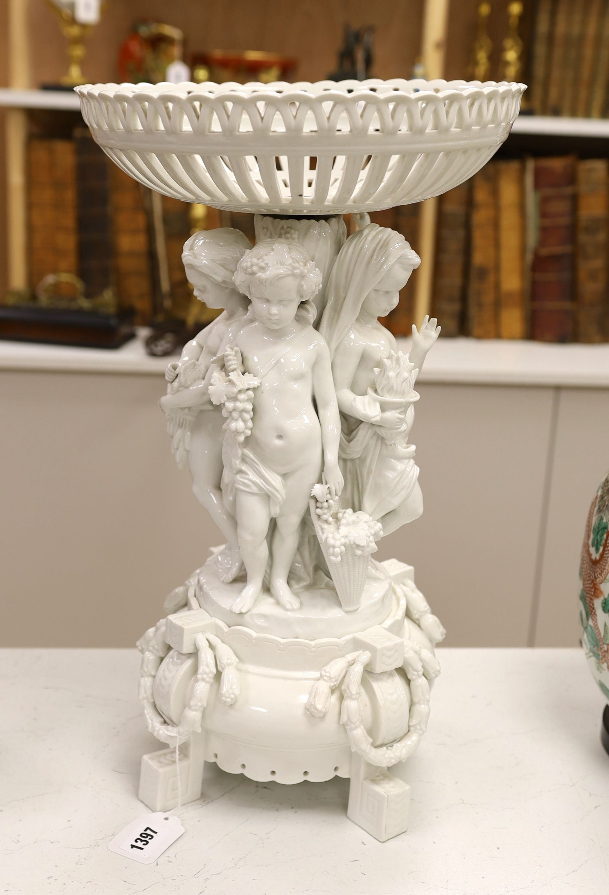 A large Continental white glazed porcelain centrepiece, the stem modelled with with figures emblematic of the four seasons, approx 53cm tall